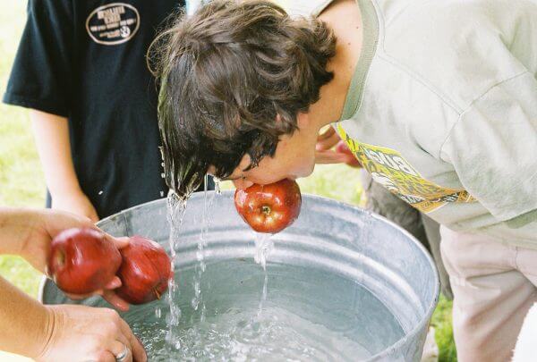 Child bobbing for apples in water
