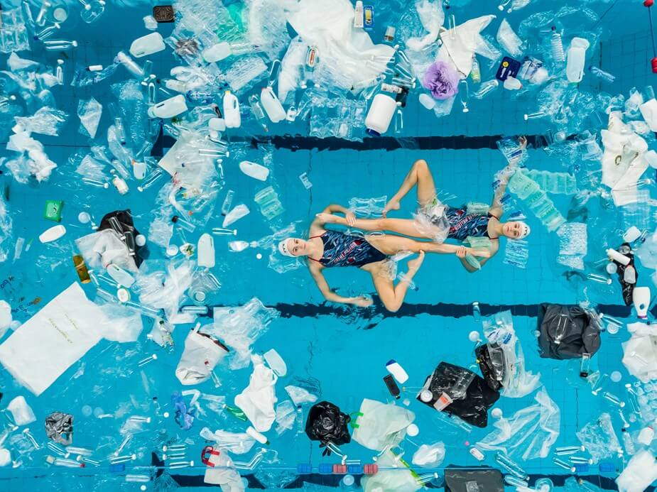 Swimmers surrounded by plastic waste.